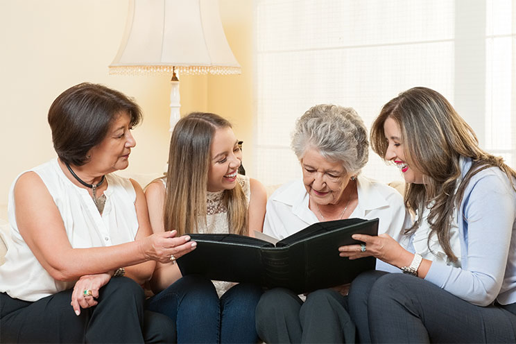 multigeneration family looking at photo album