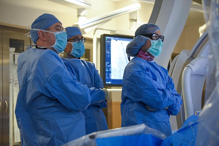 Three physicians standing in operating room