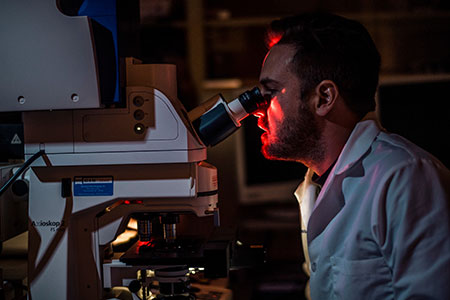 cancer researcher looking in microscope