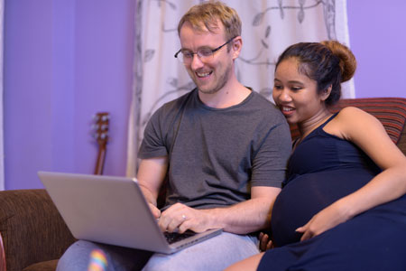 pregnant couple looking at laptop