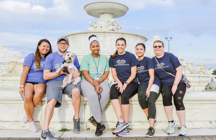 2019 Clinical Trial Team sitting on a fountain with a dog