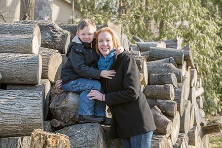 breast cancer patient erika lojko posed on wood pile with her son