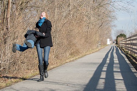 breast cancer patient erika lojko swinging her son while walking outside
