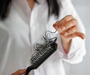 woman cleaning hair from brush