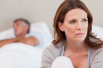 Woman looking off into the distance sitting on bed
