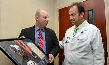 cardiology patient greg weglowski presenting marathon medal to dr farha