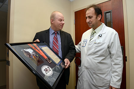 cardiology patient greg weglowski presenting marathon medal to dr farha