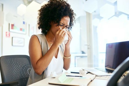 woman with rhinitis blowing her nose