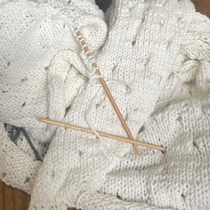 white sweater with knitting needles