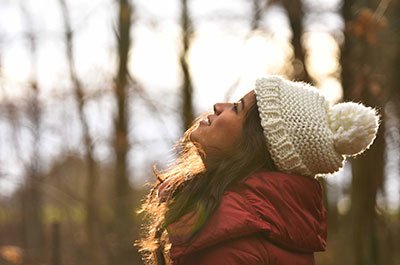 woman with hat standing in the woods
