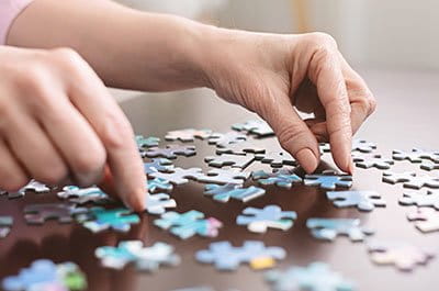woman putting together a puzzle on a wooden table