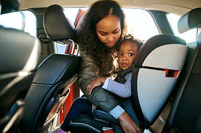 mom putting child in car seat