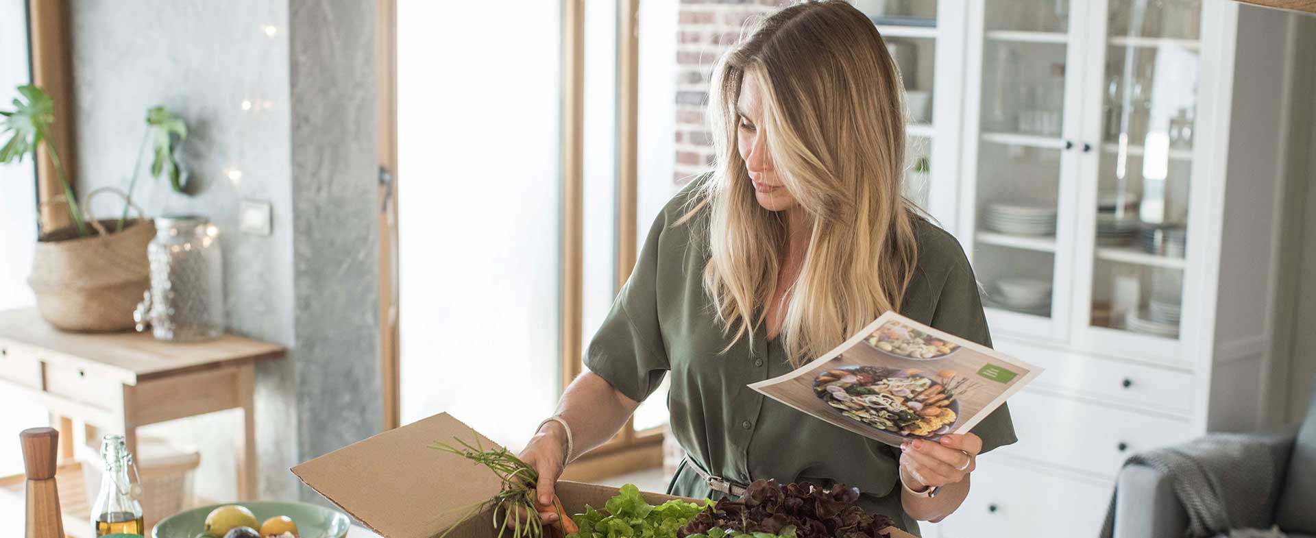 Woman opening meal kit and reviewing recipe