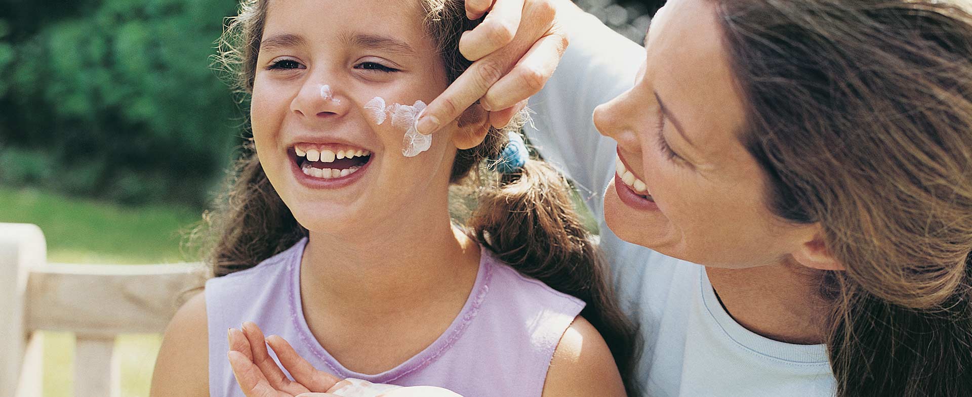 mother applying sunscreen to daughter