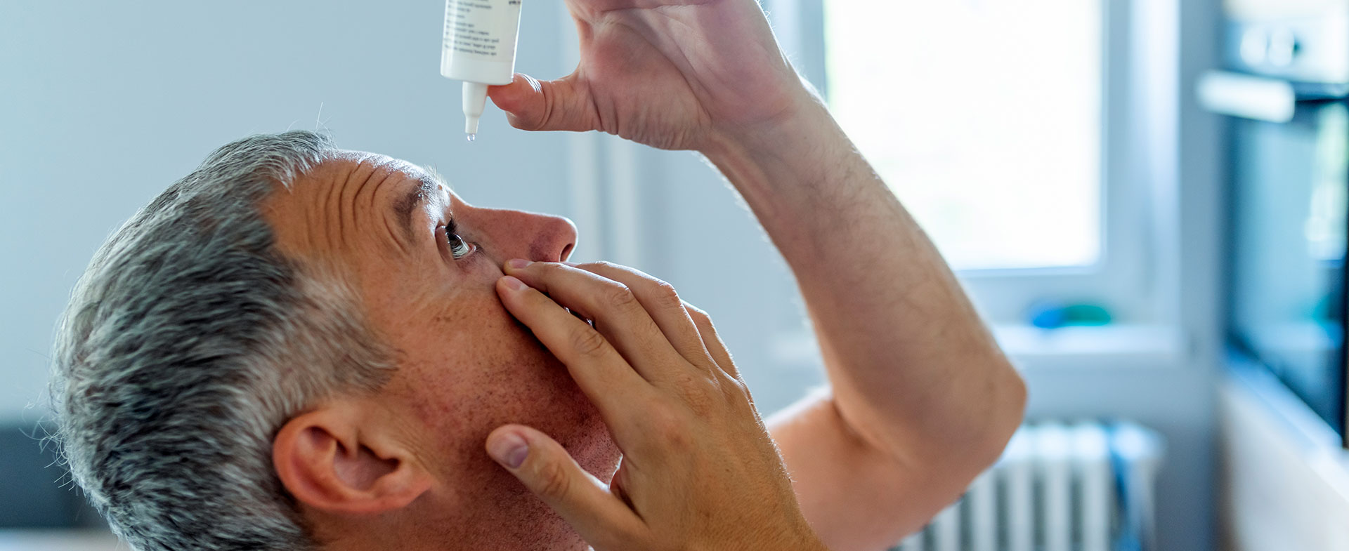man putting drops in eyes