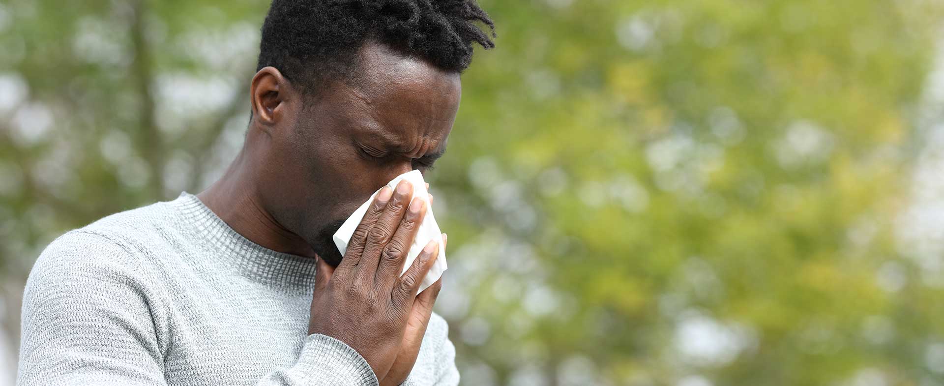 man blowing nose outside