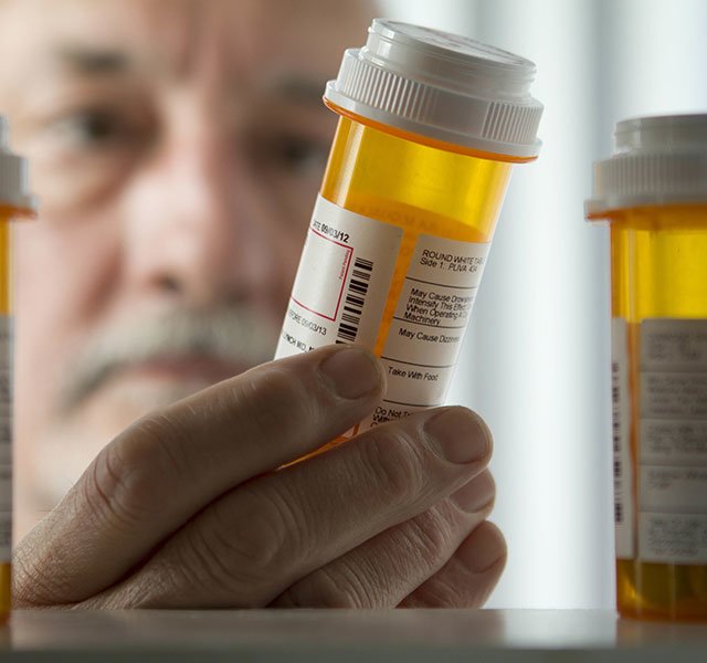 man looking at a pill bottle