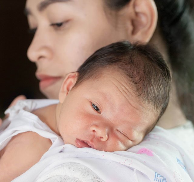 sleepy baby on mothers shoulder
