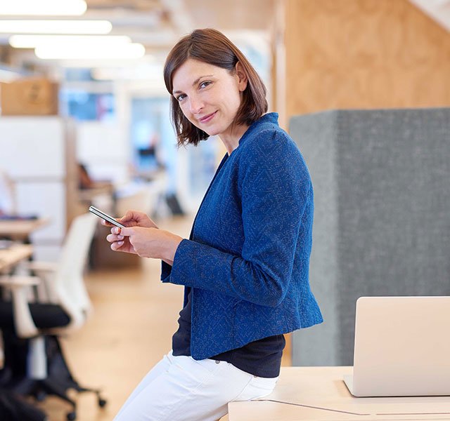 business woman smiling and holding cell phone