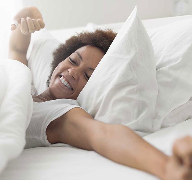 young woman in bed stretching