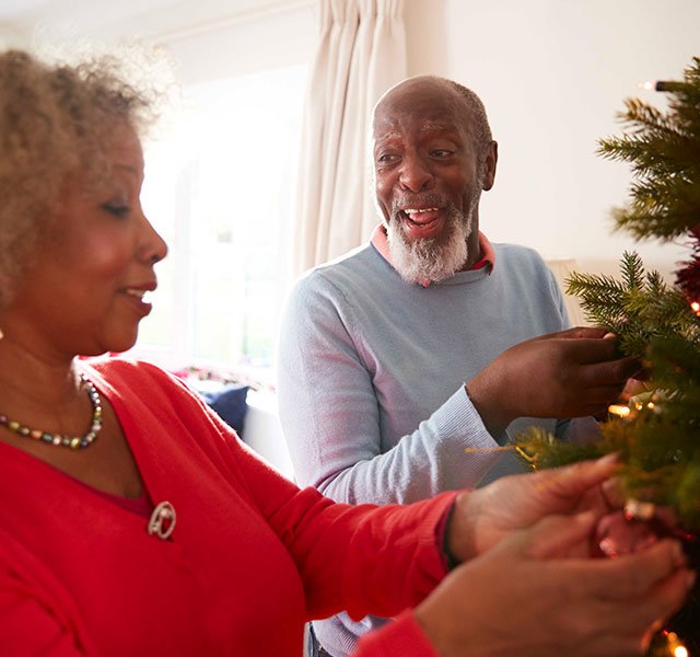 woman and man decorating a christmas tree