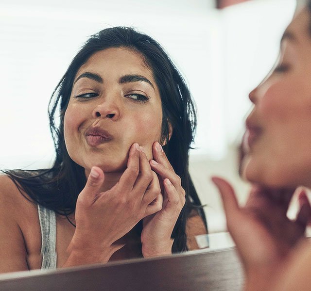 Woman looking at skin in the mirror