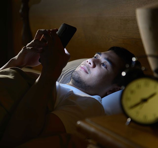 man laying in bed with phone