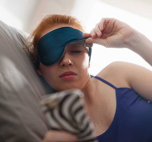 woman with sleep mask in bed