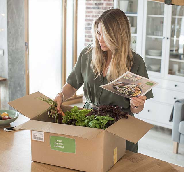 Woman opening meal kit and reviewing recipe
