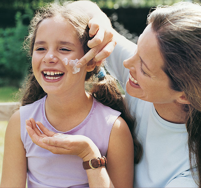mother applying sunscreen to daughter