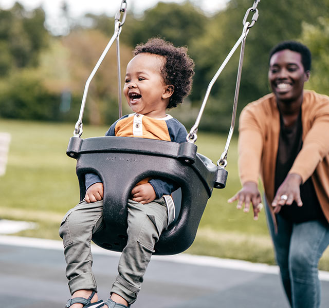 mother pushing child on swings