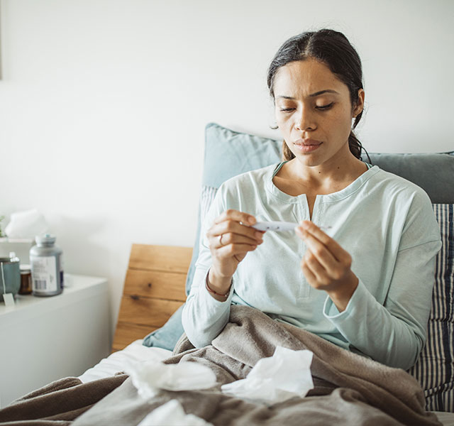 woman taking temperature in bed