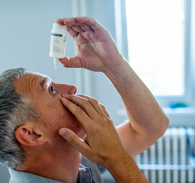 man putting drops in eyes