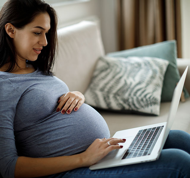 pregnant woman reading on laptop