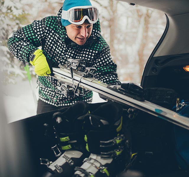 man putting skis in trunk