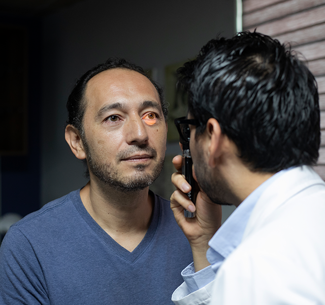 Man wearing a blue v-neck t-shirt and getting his eyes checked. man getting vision checked