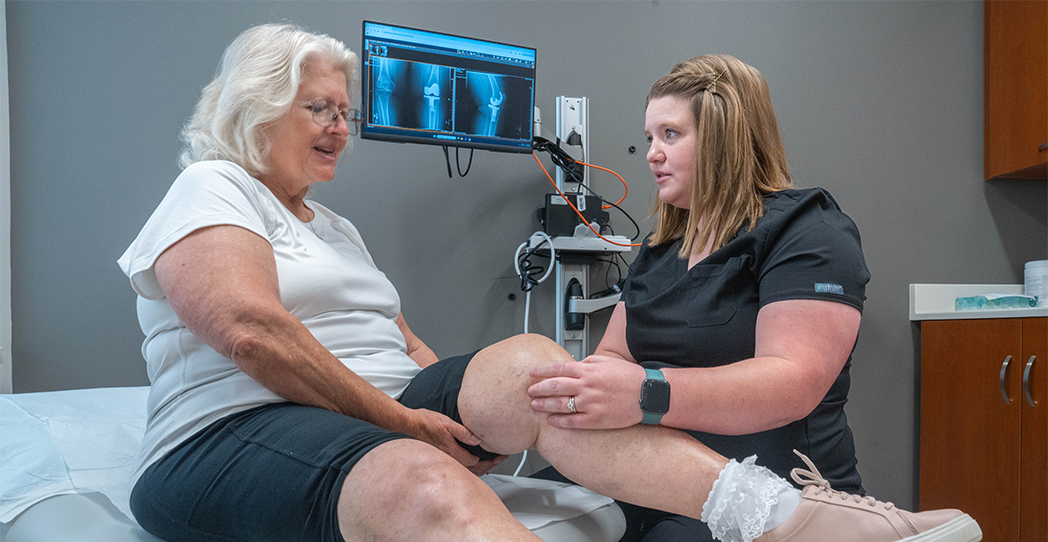 Woman and therapist looking at the woman's knee in an office.