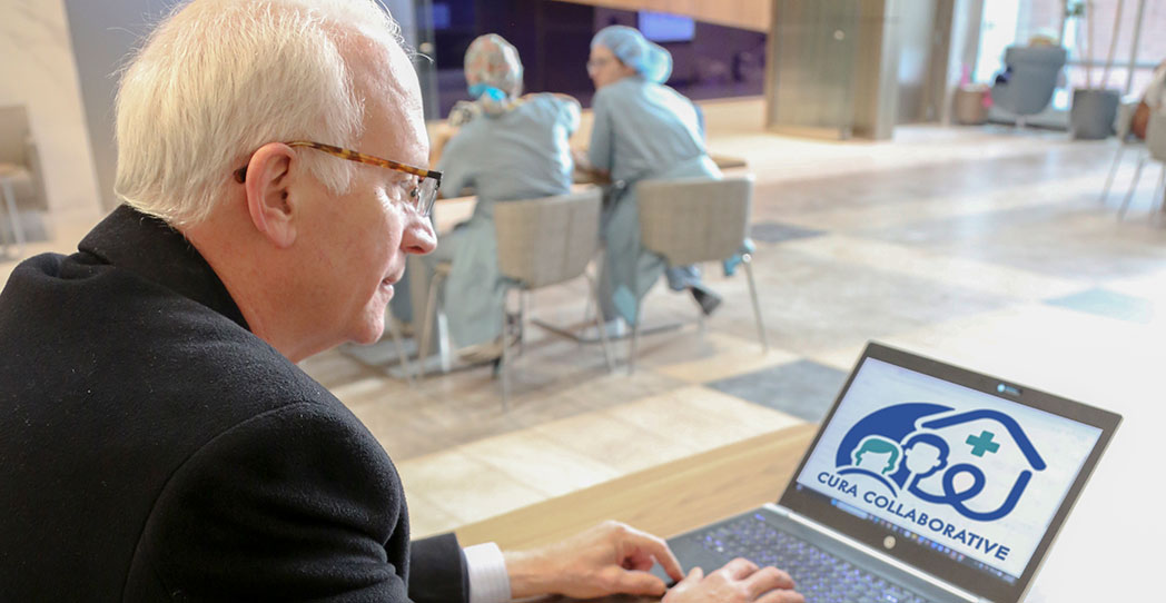 Paul with Cura Collaborative logo on laptop screen