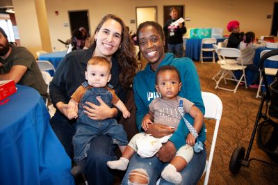 Two WIN Network participants sit next to each other holding their babies during the WIN Network Group Prenatal Care Reunion in October 2025.