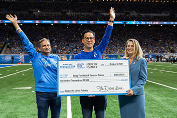 Group of people presenting a Game On Cancer donation at a Lion's game