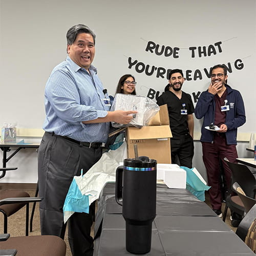 Dr. Santos opening a gift at his going away party
