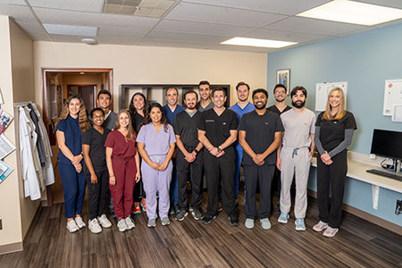 Medical residents and faculty pose for a group photograph in a clinical workspace at Henry Ford Health Seville Family Medicine clinic.