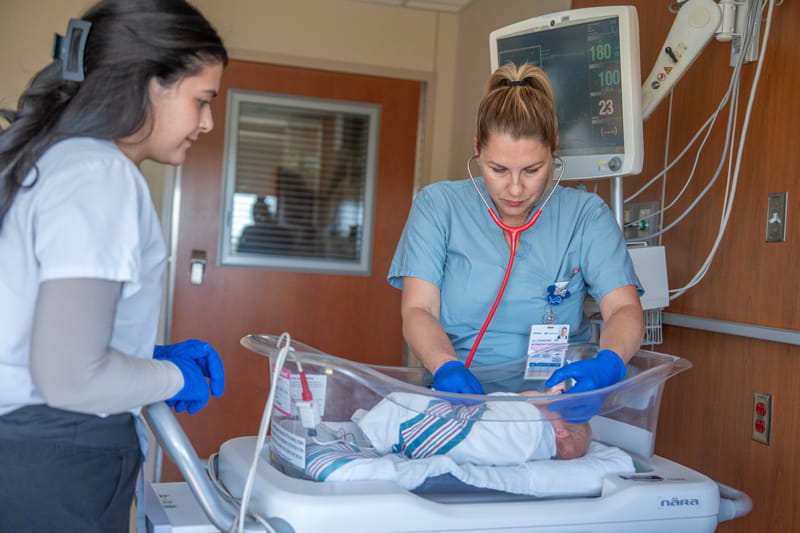 Two providers caring for a newborn baby