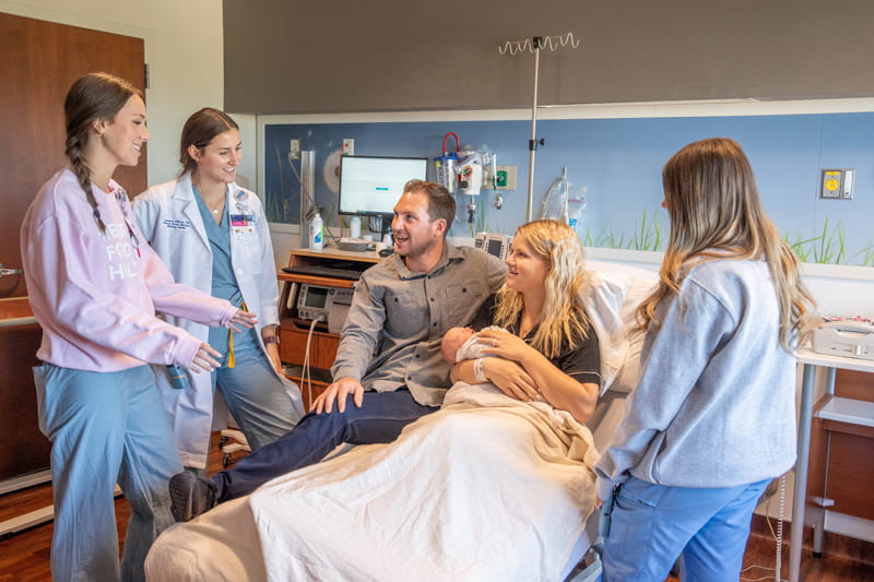 New parents holding their baby speaking with their care team