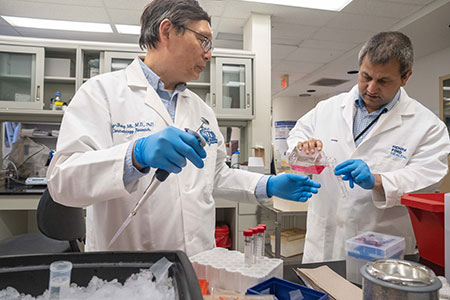 Dr. Mi handling test tubes with an assistant