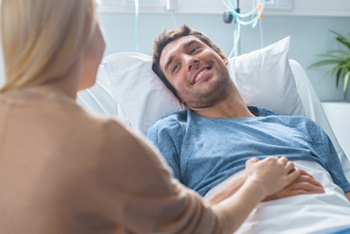 A patient laying in bed with a female visitor talking to them.