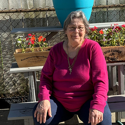 Liver cancer patient Brenda posed outside a flower garden