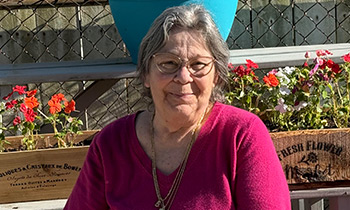 Liver cancer patient Brenda posed outside a flower garden