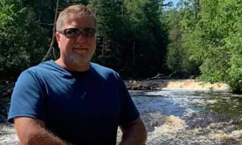 Patient Michael standing in front of a waterfall after recovery