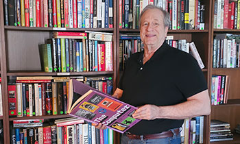 Prostate cancer patient, Ray, posing in library holding an open book